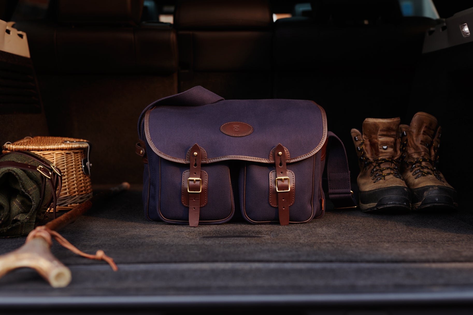 Blue leather Chapman Rambler bag with brown straps in a dark setting